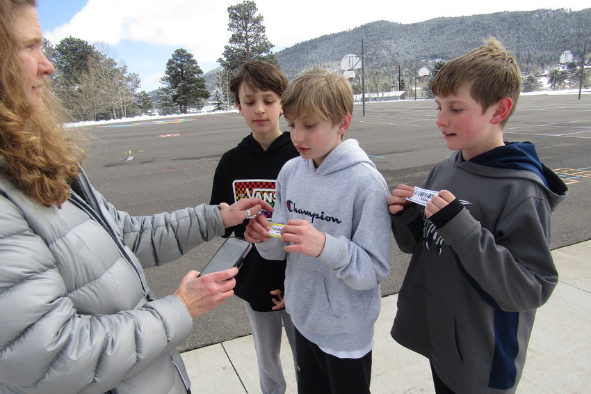 Cole Sargent, right, and his friends Rhyder Vanni and Max Diesburg have their cards scanned by 100 Mile Club coordinator Christine Olsen to track their mileage.